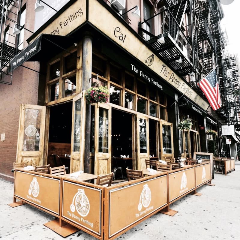 Daytime exterior of the corner pub with green awning, flower boxes and pavement terrace